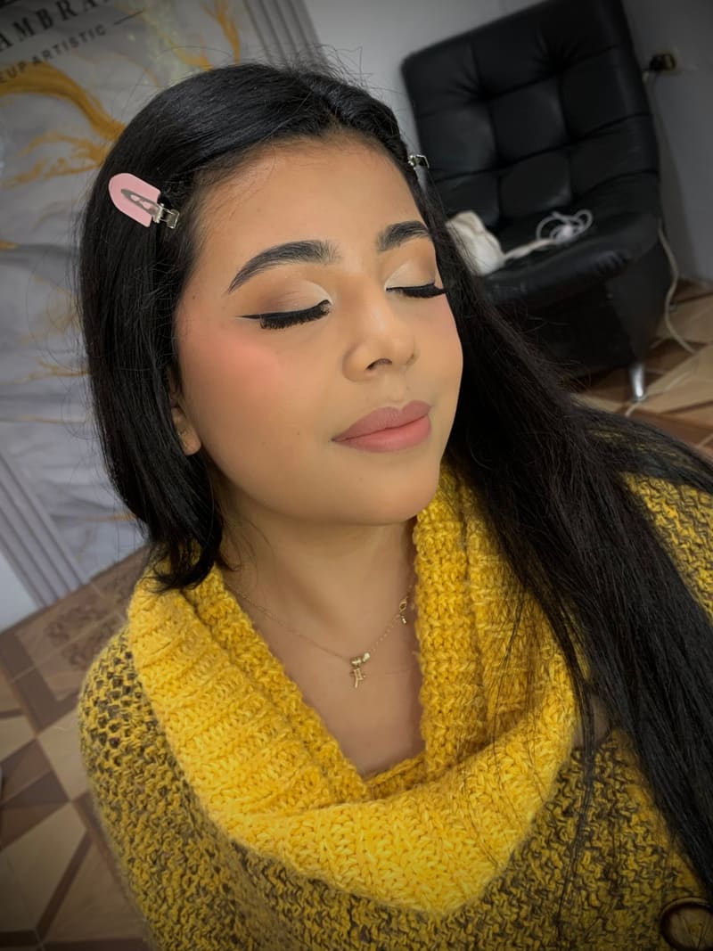 Clienta con delineado felino, sombras neutras y labios nude mate para ceremonia de grado