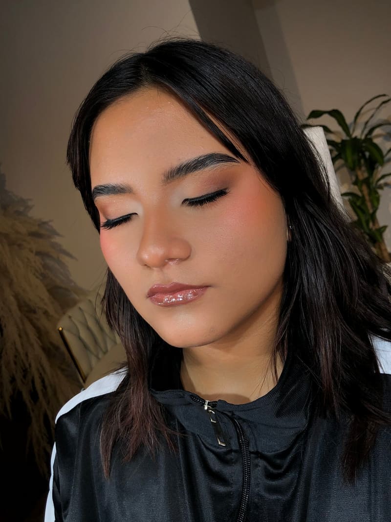 Clienta con maquillaje social de ojos esfumados en tonos cálidos y labios nude brillantes