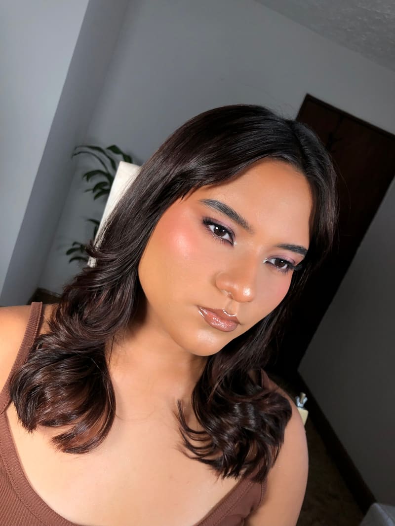 Maquillaje suave en tonos malva con piel luminosa y cabello en ondas